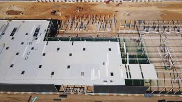 Construction site with steel frame structure of warehouse building, aerial view video