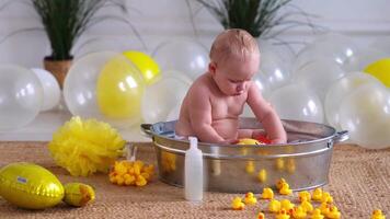 Bath time for baby, child sitting in a basin with rubber ducks video