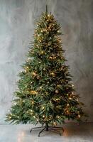 Decorated Christmas Tree With Lights and Ornaments Against a Grey Wall photo