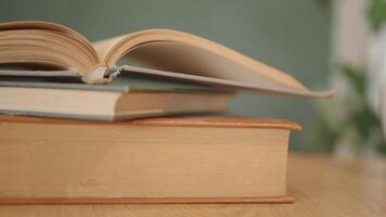An open book with its pages gently turning rests on a wooden table in the breeze video