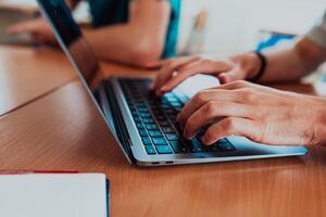In a close-up view, the fingers of a man are seen typing swiftly on a laptop keyboard, depicting a scene of focused productivity in a digital work environment photo