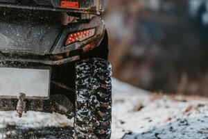 Close-up photograph, a quad rests on a snowy trail, showcasing the wintry adventure that awaits as it stands ready for an off-road journey through the frost-covered terrain photo
