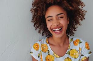 Woman With Curly Hair Smiles Against a Green Wall While Wearing a Lemon-Patterned Shirt photo