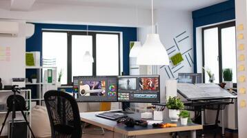 Empty modern creative agency office with dual monitors setup with processing film montage. editing start up studio company with no people in it and post production software on pc displays photo