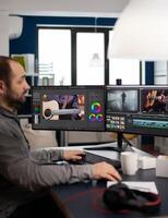 Manager production editing project working in start up creative agency office at pc with two monitors. Man processing film montage in digital multimedia company using post production software photo