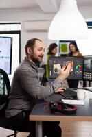 Videographer discussing online with customer holding smartphone editing film footage sitting in creative agency. Man editor processing movie montage in multimedia company with post production software photo