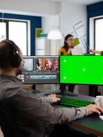 editor processing movie montage cutting footage at pc with green screen, chroma key, mock up isolated display using post production software. Videographer editing project in multimedia company photo