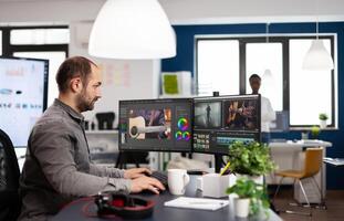 editor processing movie montage cutting footage and sound using post production software and two monitors. Man videographer editing film project in digital multimedia star up company photo