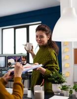 Director of creative company holding clipboard with graphics showing to videographer next customer project. editor and sound engineer working at movie montage, editing film footage in software. photo