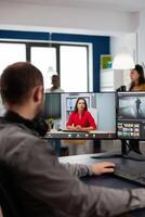 editor talking with remote customer in web online meeting using call editing project, getting feedback on commercial movie using post production program on two displays in creative agency photo