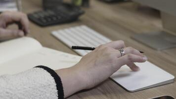 Close-up of hands at a desk working on a computer and taking notes in an office setting video