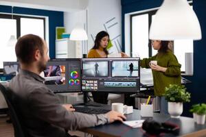 maker editing movie using post production software working in creative start up agency office with two monitors. Videographer processing audio film montage on computer in multimedia company photo