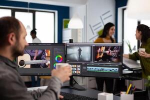 Videographer editing movie project drinking coffee using post production software working in digital multimedia company with two monitors. editor processing audio film montage on computer photo