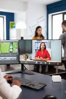Black woman videographer in web online conference with project manager on call editing client work, getting feedback on commercial movie using post production software on pc in start up office photo