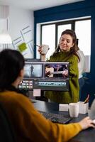 Women videographers editing project creating content, team of bloggers sitting in modern start up office studio. Manager explaning to colleaque film montage working in post production software. photo