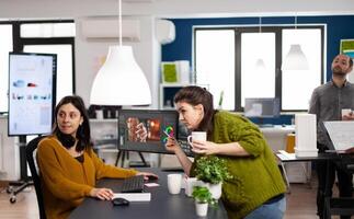 Coworkers talking about movie project looking at film footage working in creative start up agency office with two monitors. Videographers processing montage with post production software photo