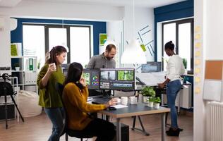 Colleagues discussing about project adjusting film footage working in creative start up agency office with two monitors. Videographers processing movie montage with post production software photo
