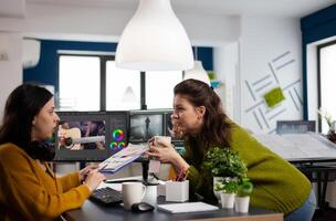 Art director explaning to woman videographer the steps for prosessing film montage showing clipboard with informations. editor working in post production software in creative agency photo