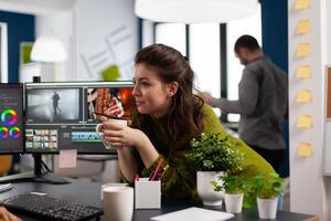 Young sound engineer working on footage during post production talking with colleague. Content creator editing montage of film using modern software for processing sharing ideas with coworker photo