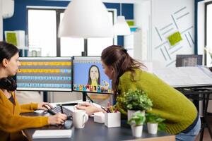 Art director consulting designer colleague, retouching portrait in photo editing software working in creative agency. Retouchers talking, color grading assets using graphic tablet with stylus pen