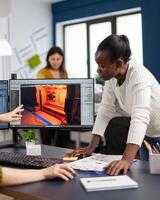 Mixed races of game creators testing the interface of videogame, analysing software problems. Diverse team developing project sitting in startup creative agency company using pc with two monitors photo