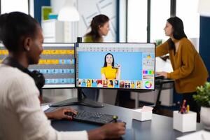 African creative photographer using digital retouching program, editing photos for client in creative office. Retoucher, graphic editor working in digital multimedia workplace at pc with two monitors