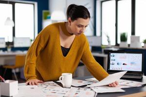 Project leader preparing presenstation for investors using printed charts. Executive entrepreneur, manager leader standing working on documents projects. photo