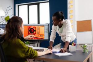 Diverse women game sofware developers testing new game sitting in startup creative agency company using pc with dual monitors setup. Workers developing new online games with modern technology photo