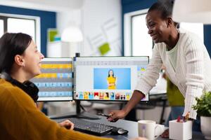 Exited diverse team of women retouchers working with photo editing software in digital multimedia company, discussing and laughing. Art director consulting designer colleague, retouching portrait