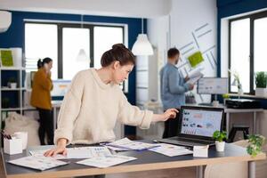 Businesswoman analysing financial statistics standing in start up office. Executive entrepreneur, manager leader standing working on projects with diverse colleagues. Successful corporate professional entrepreneur online internet statistics photo