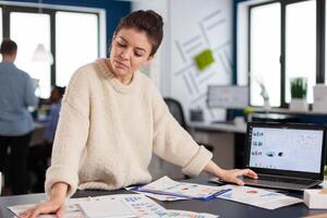 Financial charts analysed in start up company by business owner standing at desk. Successful corporate professional entrepreneur online internet statistics, Executive entrepreneur, manager leader standing working on projects with diverse colleagues. photo