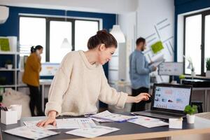 Business analyst working on new financial strategy looking at laptop display. Executive entrepreneur, manager leader standing working on projects with diverse colleagues. Successful corporate professional entrepreneur online internet statistics photo