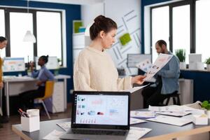 Corporate businesswoman reading statistics in start up company office. Successful corporate professional entrepreneur online internet statistics. Executive entrepreneur, manager leader standing working on projects with diverse colleagues. photo
