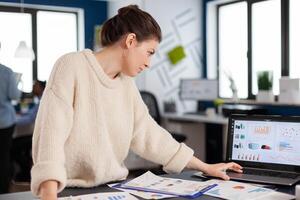 Company manager reading, analysing statistics on laptop in start up office. Executive entrepreneur, manager leader standing working on projects with diverse colleagues. Successful corporate professional entrepreneur online internet statistics photo