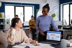 Diverse business colleagues discussing briefing financial statistics, reading charts on documents of start up company. Multiethnic employees gathered in co-working space. photo