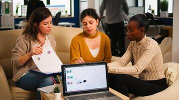 African woman talking about project, discussing start up ideas using pc, diverse employees gathered in co-working, working process in busy company. teamwork help concept photo