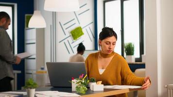 Satisfied manager checking financial statistics and graphs typing on laptop sitting at desk working in financial startup company. Diverse team analyzes statistics data in modern office photo