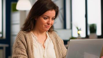 Close up of authentic happy professional employee sending mails sitting at desk in front of lapotop smiling, working financial startup company. Diverse team analyzes statistics data in modern office photo