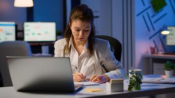 Business woman working overtime to respect deadline of project sitting in business office typing on laptop late at night. Busy focused employee using modern technology network wireless searching photo