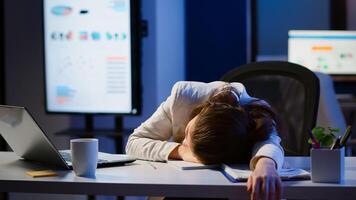 Freelancer working overtime on project falling asleep on desk with hand on financial documents trying to respect the deadline. Employee using modern technology network wireless, sleeping on table. photo