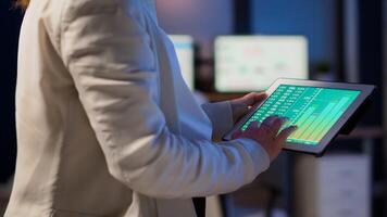 Close-up photo of woman hands holding tablet computer analysing graphs standing in start-up office late at night. Business woman using social network, texting and blogging working overtime for job