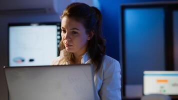 Freelancer typing on laptop late at night standing in start up business office late at night working. Busy focused employee using modern technology network wireless doing overtime for job searching photo