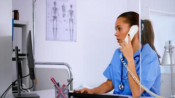 Specialist healthcare physician talking at phone in medicine clinic, receptionist doctor assistant helping with telehealth concultation. Nurse working in hospital checking registration on computer photo