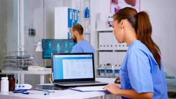 Doctor assistant checking list diagnosed of patients, writing on clipboard with x-ray and medical equipment around. Physician working in hospital making appointments and analysing patient registration photo