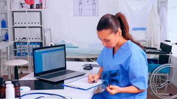 Nurse checking x-ray result, reading patients list, taking notes in clipboard holding radiography. Medical physician in medicine uniform writing list of consulted, diagnosed patients, making research. photo