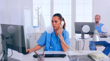 Woman receptionist answering at phone, working in hospital clinic writing on computer, making appointments. Medical physician in uniform writing list of consulted, diagnosed patients, making research. photo