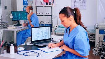 Group of nurses working in hospital office, analysing digital human skeleton presentation and body scan. Medical physician in medicine uniform writing list of consulted, diagnosed patients, making research. photo