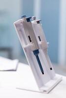 Medical micropipette standing on table ready for microbiology scientific test experiment in biology science hospital laboratory. Clinical biological instrument. Healthcare investigation photo