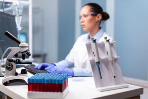 Microbiology scientist typing biochemistry discovery experiment at computer using medical high tech working in pharmacology hospital laboratory.Biology doctor developing virus treatment expetise photo