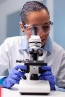 Scientist woman doctor looking at coronavirus genetics test using medical microscope working at bacteriology experiment in hospital laboratory. Researcher microbiologist discovering medicine vaccine photo